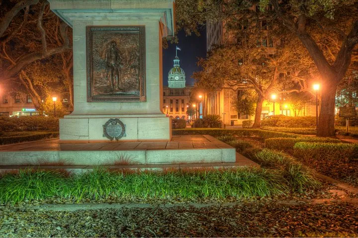 A monument in a Savannah square lit at night, the meeting point of an adults-only ghost tour in Savannah GA