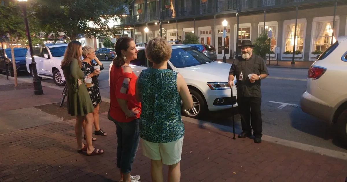 A small group with a guide on a Savannah street at dusk on a haunted pub crawl ghost tour in Savannah GA
